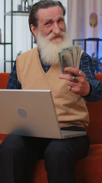 予算の計画 金持ちの幸せな高齢者の祖父の計算お金の現金を使用ノートパソコン家庭で国内請求書を計算します 楽しい高齢者の収入に満足し 計画休暇の贈り物のためのお金を節約 — ストック写真