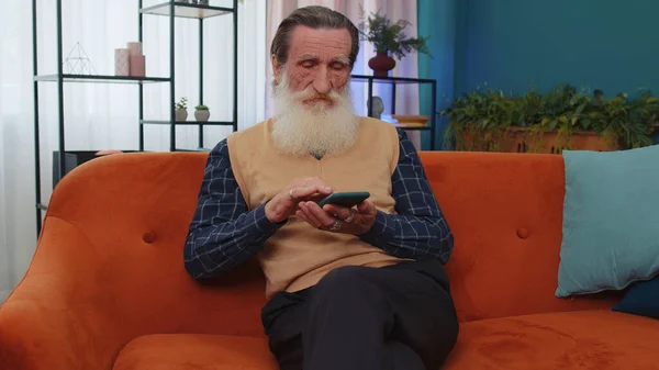 Senior Grandfather Sitting Sofa Uses Smartphone Smile Home Elderly Man — Stock Photo, Image