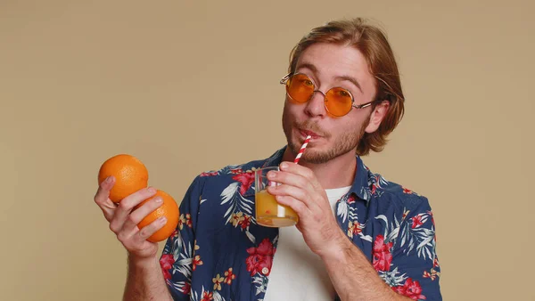 観光の若い男を保持 健康のためのオレンジフルーツ 菜食主義者のライフスタイル ビタミン 幸せな休暇の休日 有機エコ食品 わらからジュースを飲んでいます 若いです男男の子オンベージュ背景 — ストック写真