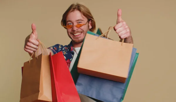 小切手シャツで幸せな観光客の男性は 低価格で ブラックフライデーの休日に買い物に驚いて見て笑顔のショッピングバッグ 広告割引を示しています 若いですBeaded男男の子オンベージュ背景 — ストック写真