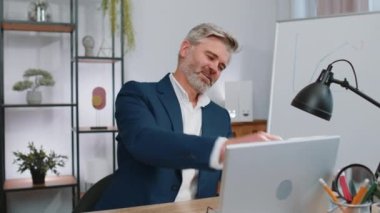 Olgun yaşlı iş adamı güneş gözlüğü takıyor, şenlik şapkası takıyor, iş yerinde şampanya içiyor zafer dansı yapıyor, hafta sonu. Proje geliştirme sevinci. Başarıyı kutluyoruz. Piyango ikramiyesi. Ofisteki insanlar