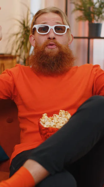 红头发兴奋的年轻人坐在沙发上吃爆米花 在家里看有趣的电视连续剧 体育游戏 在线社交媒体电影内容 享受家庭娱乐的男人 — 图库照片