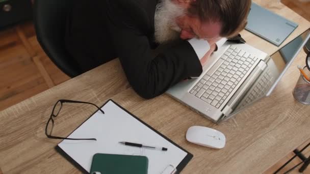 オフィスのデスクでラップトップ上のルーチン作業の後に眠りに落ちる正式な摩耗スーツで眠そうな高齢者のビジネスマンプログラマーソフトウェア開発者を退屈 疲れきったフリーランスのサラリーマン — ストック動画
