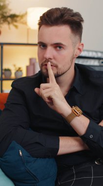 Sessiz olun lütfen. Beyaz sakallı bir adamın portresi işaret parmağını dudaklarına bastırır. Sessiz ol işareti dedikodu sırrını söylemez. Sınıftaki genç adam kanepede oturuyor. Dikey çekim