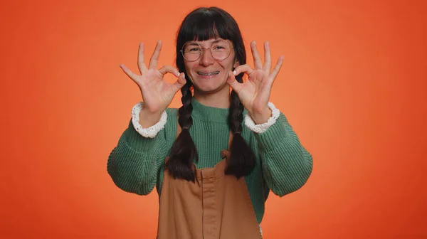 Ok. Joyful happy one woman in sweater looking approvingly at camera showing approve feedback gesture, like sign positive something good. Young girl on orange studio background. People sincere emotion