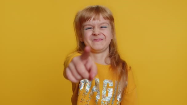 カメラに指を指して 大声で笑い ばかばかしい外観 面白い冗談の楽しさを試みている若い未成年の少女の子供を驚かせた 黄色の背景に一人で孤立した小さな幼児 — ストック動画