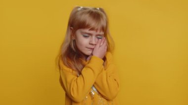 Dental problems. Young preteen child girl kid touching cheek, closing eyes with expression of terrible suffer from painful toothache, sensitive teeth, cavities. Toddler children on yellow background