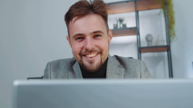 Close-up portrait face businessman freelancer in suit at office workplace, working on laptop computer. Manager freelancer man works on notebook, sends messages makes online purchases watching movies