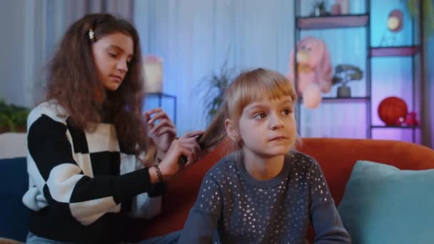 十几岁的孩子和妹妹们用梳子刷孩子们的头发 做发型 兄弟姐妹 孩子或好友在家里的游戏室里梳理长发 家人打盹派对 — 图库视频影像