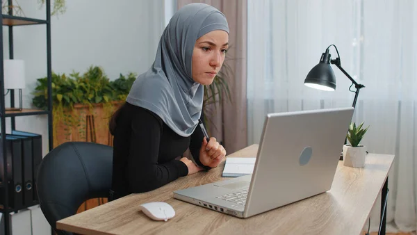 Muslim business woman in hijab study with notebook at home office on laptop computer making conference video call talking to webcam. Online teacher e-learning in remote chat. Distance education online