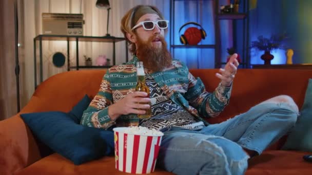 Podekscytowany Brodaty Hipis Młody Człowiek Siedzi Kanapie Jedząc Popcorn Przekąski — Wideo stockowe