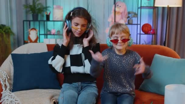Девочки Младшей Сестры Стильных Солнцезащитных Очках Слушают Музыку Наушниках Танцуют — стоковое видео
