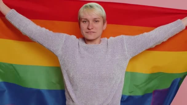虹のLgbtフラグでポーズ短い髪を持つ千年の女性は パレードを祝う同じ寛容を示しています性別結婚 ピンクのスタジオの背景に孤立した若い女の子 バイセクシャルゲイレズビアンの人々の概念 — ストック動画