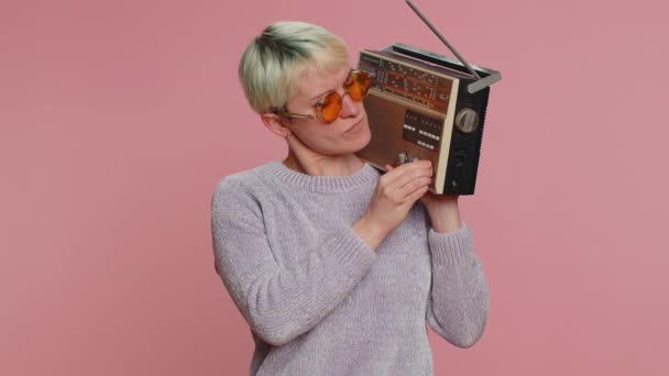 千年妇女的短发使用复古磁带唱机听音乐 迪斯科舞蹈最喜欢的曲目 有乐趣 娱乐性 老式技术的粉丝 粉红背景的少女 — 图库视频影像