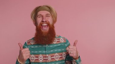 Hoş, neşeli, kızıl saçlı, şablon tişörtlü sakallı adam önerini çok beğeniyor, başını sallıyor, kaliteli işlerden memnun, evlenme teklifi gibi. Pembe arka plandaki hippi.