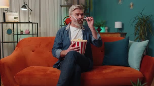 Ενθουσιασμένος Ώριμος Άνδρας Κάθεται Στον Καναπέ Τρώγοντας Σνακ Ποπ Κορν — Αρχείο Βίντεο