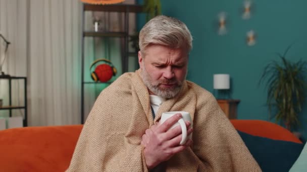 Hombre Enfermo Envuelto Cuadros Sienta Solo Temblando Frío Sofá Bebiendo — Vídeo de stock