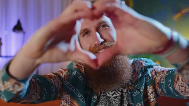 사랑해 수염의 히피붉은 남자가 소파에서 사랑의 상징을 만들고 카메라에 표시를 — 비디오