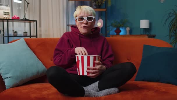 Ενθουσιασμένη Γυναίκα Ξανθά Μαλλιά Κάθεται Στον Καναπέ Τρώγοντας Σνακ Ποπ — Αρχείο Βίντεο