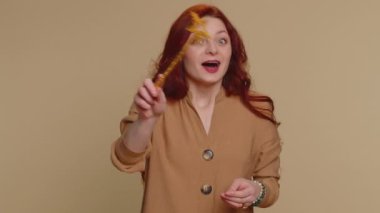 Sihirli değnek ve sihirli değnekle hareket eden büyücü kadın dileği gerçekleştiriyor, sihirbaz büyüsü yapıyor, tatil indirimi yapıyor. Genç kızıl saçlı kız bej renkli stüdyo arka planında izole edilmiş.