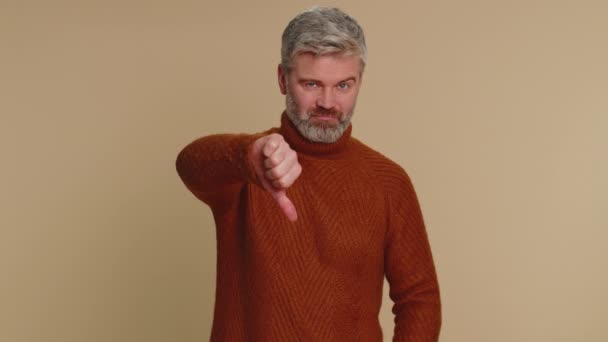 嫌いだ 動揺不幸な中年の男性のセーターの親指を看板ジェスチャーを示す 嫌いな表現 大人の男だ 室内スタジオショットオンベージュ背景 — ストック動画