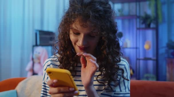 Žena Kudrnatým Účesem Sedící Pohovce Používá Mobilní Telefon Úsměvy Nočním — Stock video
