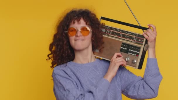 卷发女人用复古磁带唱机听音乐 迪斯科舞最喜欢的曲目 有乐趣 老式技术的粉丝 被黄色背景隔离的少女 — 图库视频影像