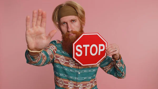 No stop. Serious hippie man say No, hold inscription text red No stop danger sign, warning of finish, prohibited access declining communication, body language, trouble, protest. Guy on pink background