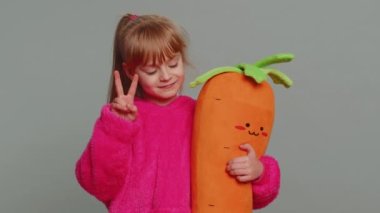 Young preteen child girl kid showing victory sign, hoping for success and win, doing peace gesture, smiling with kind optimistic expression. Little toddler children on studio gray background