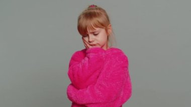 Dental problems. Young preteen child girl kid touching cheek, closing eyes with expression of terrible suffer from painful toothache, sensitive teeth, cavities. Toddler children on gray background