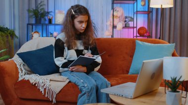 Evde dizüstü bilgisayarla konferans görüntülü konuşma yapan genç kız öğrenci serbest yazar çalışması. Çevrimiçi öğretmen uzaktan sohbette e-öğreniyor. Çevrimiçi uzaktan eğitim