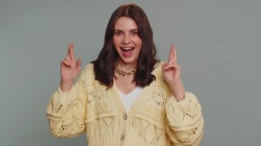 Happy joyful pretty woman with crossed fingers, shouting, raising fists in gesture I did it, celebrating success, winning, birthday, lottery jackpot goal achievemen. Girl on gray studio background
