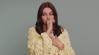 I will not say anyone. Frightened woman closing her mouth with hand, looking intimidated scared at camera, gestures no, refusing to tell terrible secret, unbelievable truth. Girl on gray background