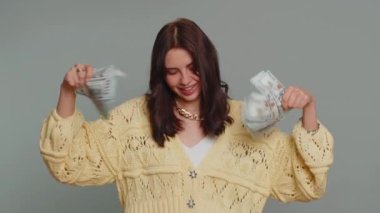 Rich pleased boss millennial woman waving money dollar cash banknotes bills like a fan, success business career, lottery winner, big income, wealth. Young pretty girl isolated on gray background