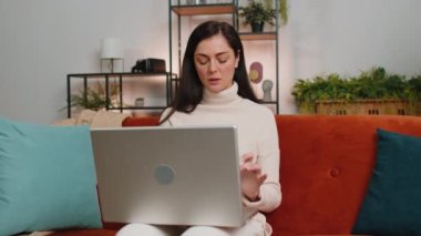 Displeased brunette woman use laptop notebook typing browsing working, loses becoming surprised sudden lottery results bad news, fortune loss fail, computer virus. Girl at home in living room on couch