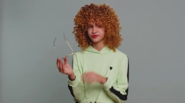 Exhausted tired teenager school girl with curly frizzy hairstyle takes off glasses, feels eyes pain, being overwork burnout from long hours studying or working. Child kid isolated on gray background