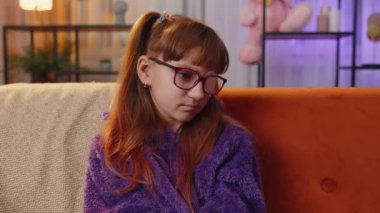 Sick ill preteen girl looking at camera, having protective bandage plaster patch scratch on one eye. Injury, trauma, blind. Child kid wearing glasses at home in room. Medical eyesight vision therapy