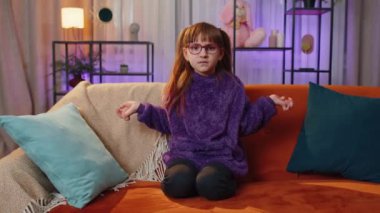 What. Why. Toddler girl raising hands in indignant expression, asking reason of failure, demonstrating disbelief irritation by troubles. Teen child kid at home in evening living play room on couch