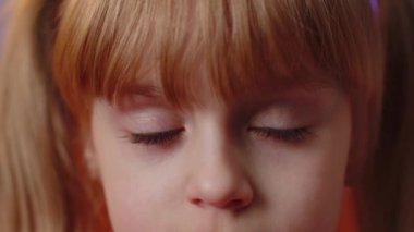 Extreme close-up macro portrait of smiling girl face. Teen beautiful kids eyes looking at camera. Young positive toddler child opening wide her closed eyes. Brown eyes of blonde female children model