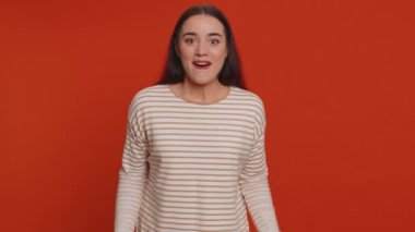 Happy joyful pretty woman in pullover shouting, raising fists in gesture I did it, celebrating success, winning, birthday, lottery jackpot goal achievemen. Adult girl indoors on red studio background