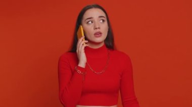 Lovely woman tired sleepy freelancer talking on mobile phone with friend, making online conversation. Disinterested sad young girl having annoyed boring talk on smartphone on red studio background