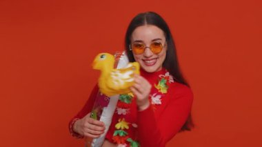Traveler tourist young woman celebrating, dancing fooling with swimming inflatable duck toy. Concept summer vacation, journey, trip to seaside. Lovely girl in sunglasses on red studio background