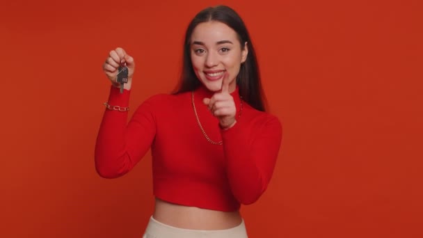 新しい家のアパートの鍵を示す手を持ち上げる作物の上の不動産屋の若い女性 不動産を購入 住宅ローン 赤いスタジオの背景に隔離された千年の少女 — ストック動画