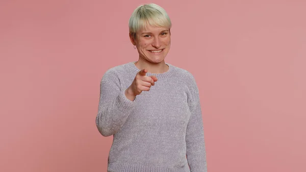 I choose you. Young woman with short hair smiling excitedly, pointing to camera, choosing lucky lottery winner, indicating to awesome you. Girl isolated on pink background. Lgbt gay lesbian people