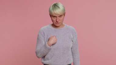 I am watching you. Caucasian woman with short hair pointing at her eyes and camera, show I am watching you gesture, spying on someone. Young girl on pink studio background. Lgbt gay lesbian people