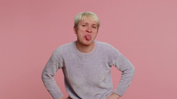 カメラで顔を作る舌を示す短い髪を持つ面白い女性は 周りを欺く 愚かな顔で からかう冗談 ピンクのスタジオの背景に孤立した若い女の子 Lgbtゲイレズビアンの人々の概念 — ストック動画