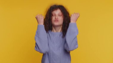 Angry woman screams yell from stress tension problems feels horror hopelessness fear panic surprise shock expresses gestures rage. Young pretty curly haired girl isolated on yellow studio background