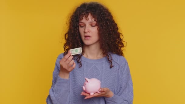 Poor Young Curly Haired Woman Insufficient Amount Money Holding Piggybank — Vídeos de Stock