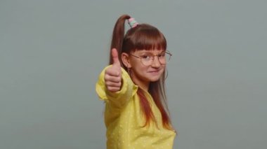 Like. Happy young preteen child girl kid looking approvingly at camera showing thumbs up, like sign positive something good, positive feedback. Toddler children isolated on studio gray background