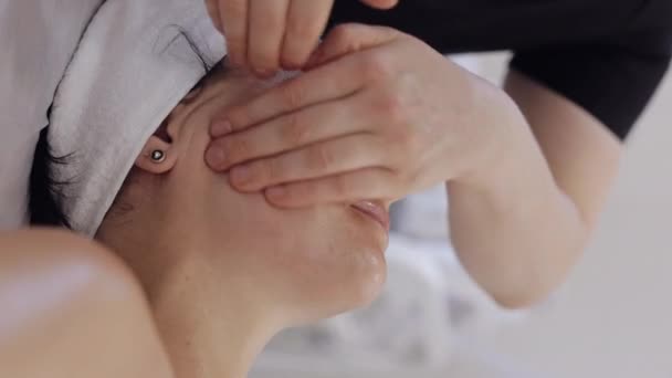 治疗师医生让女人放松 用手按摩面颊 美容院提供光滑 健康的护肤治疗 排毒和愈合 面部物理美容术课程的客户 垂直射击 — 图库视频影像